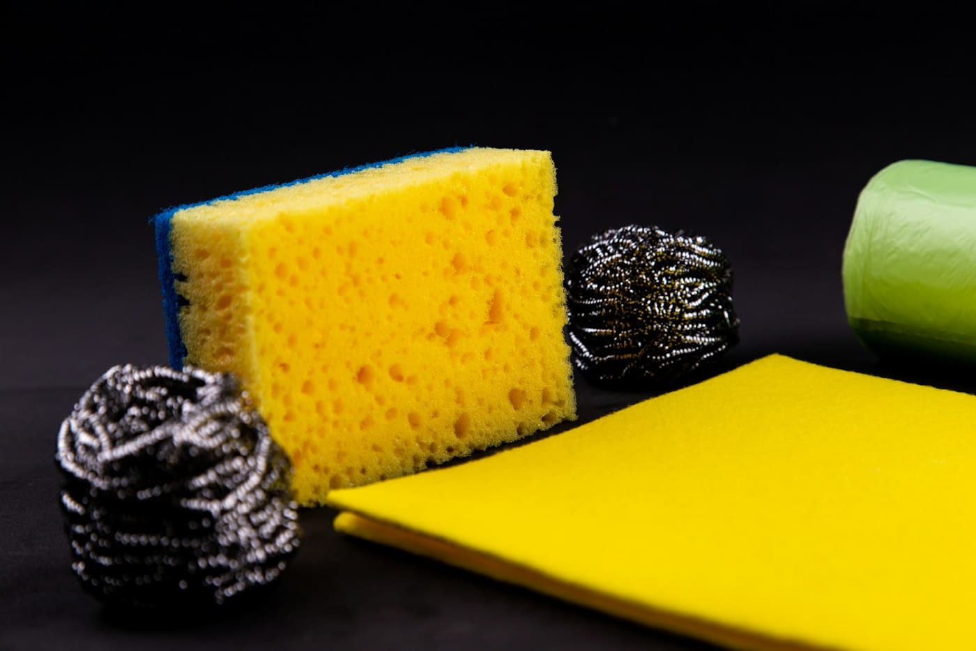 A kitchen sponge beside two steel-wool scourers