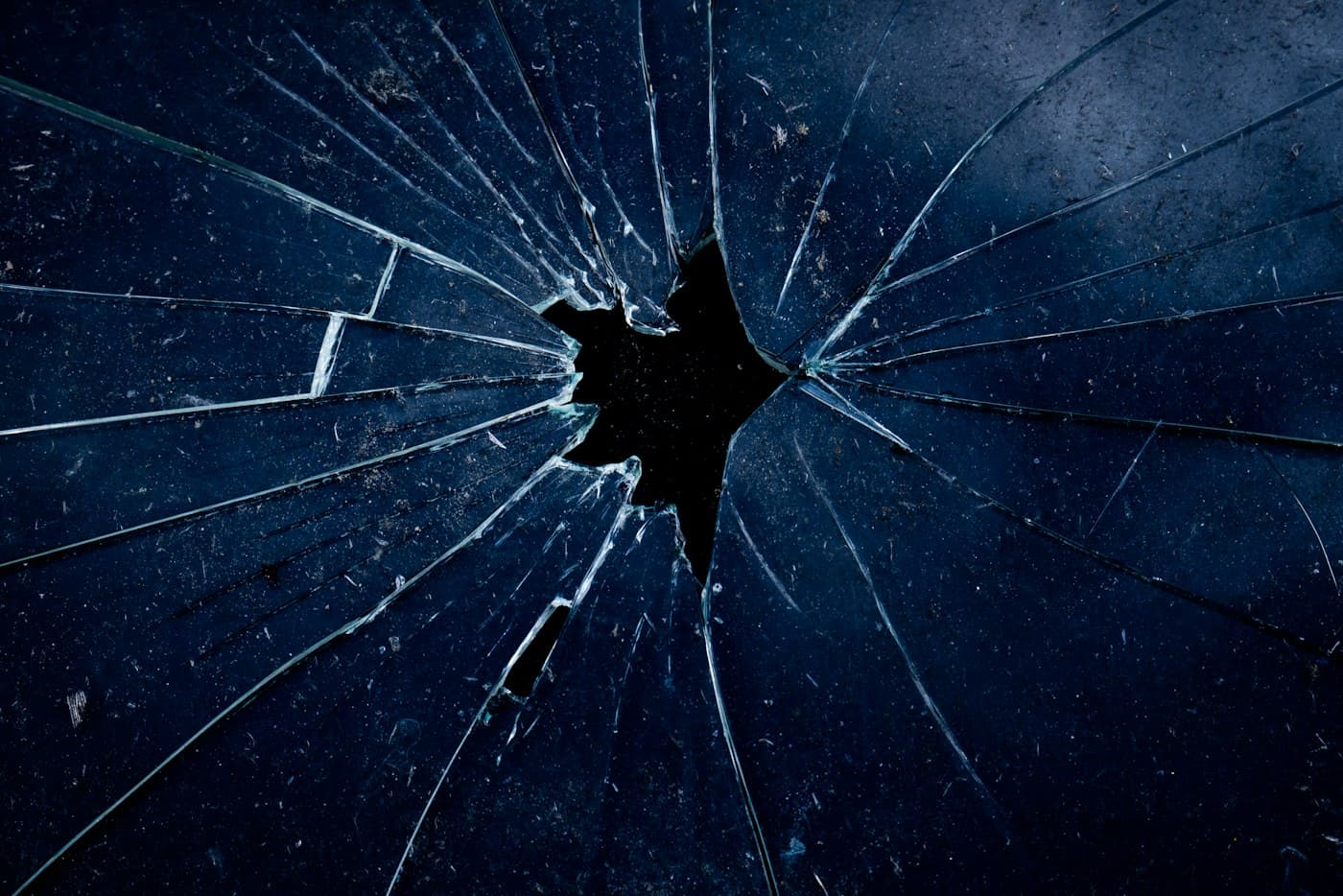 Dark blue glass with cracks radiating from a central impact point