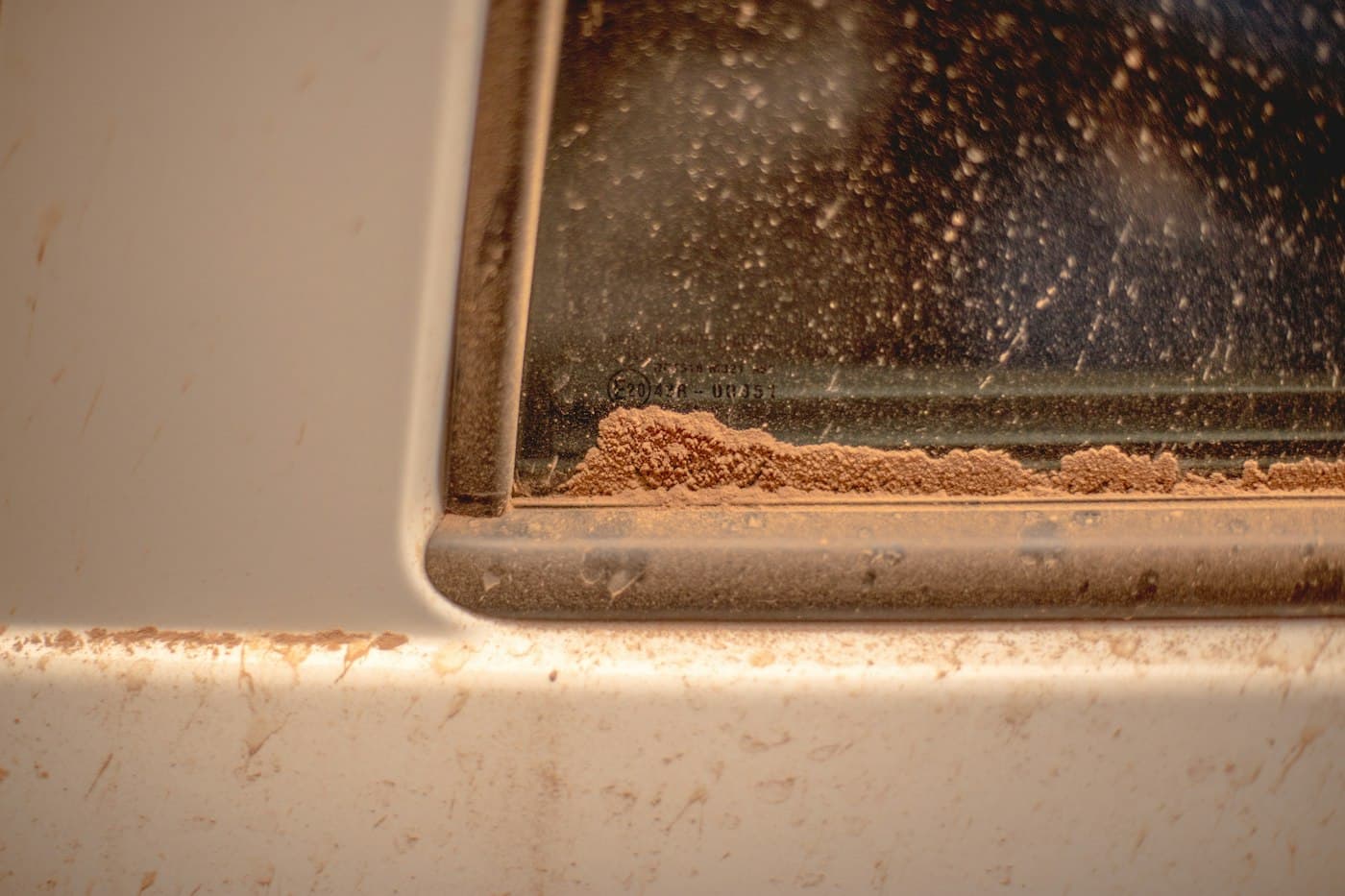 Dried dust and mineral residue caked along the edge of a glass pane